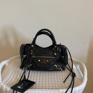 Svart Balenciaga handväska i skinn - Fin äkta balenciaga handväska jag säljer för jag har tröttnat, liten defekt i spegeln då den spruckit lite. Skriv för fler bilder 