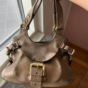 Vintage Brun axelväska i skinn från Mulberry - Elegant Vintage brun Mulberry axelväska i kraftigt, grynigt läder med vackra mässingsdetaljer och klassiskt spänne framtill. Mått: 32 x 24 x 17 cm.