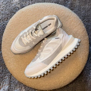 Axel Arigato Sonar Vit - Oanvända snygga ”sonar” sneakers från Axel Arigato i vitt och ljusgrått med coola detaljer. Ovandel i mocka och textil, robust sula med grovt mönster och klassisk snörning. Perfekta för dig som gillar stilrena och trendiga skor med sportig vibe. Nypris 3050kr, säljer för 1499kr.