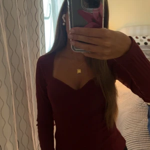 Vinröd ribbad långärmad topp - Vinröd ribbad topp med lång ärm och snygg sweetheart-urringning. Figurnära passform som framhäver siluetten och ger en trendig look. Perfekt för dig som gillar stilrena och enkla plagg med det lilla extra.