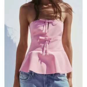 Rosa axelbandslös topp med rosetter - Supersöt rosa bandaeu topp med knytningar. Helt ny och oanvänd med prislappen kvar💗
