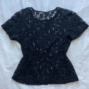 Svart spetstopp - Supersnygg svart topp i spets med blommigt mönster. Kortärmad och figurnära passform, perfekt att styla över ett linne eller under T-shirt!! Vet inte vart den är ifrån då lapparna är bortklippta💓