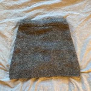 Grå stickad kortkjol - Mysig grå stickad kortkjol med enkel och stilren design. Kjolen har en rak passform och ribbad kant nedtill, perfekt att matcha med en oversized tröja eller boots för en chill look.