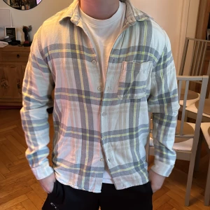 Beige rutig skjorta från Zara - Snygg beige skjorta med rutigt mönster i grått och gult från Zara.  Skjortan har klassisk krage, bröstficka och knäppning. Perfekt för en avslappnad och trendig look.