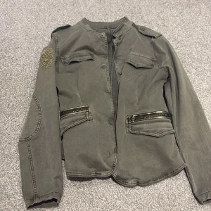 Grön jeans jacka  - Grön jeans jacka med tryck i guld, står ej storlek men skulle gissa på s 
