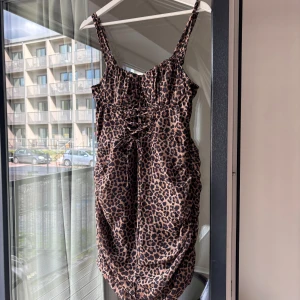 Nakd klänning   - Leopardmönstrad mini klänning från NaKd. Justerbara axelband och knytning vid bysten. Aldrig använd, prislapp kvar. 