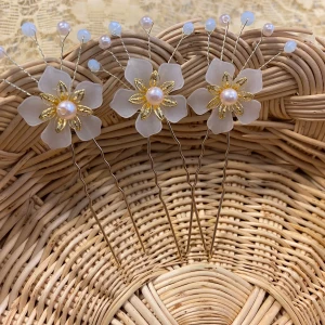 Blommiga hårnålar med pärlor och guld - Tre hårnålar med vita blommor i frostat material, dekorerade med guldfärgade detaljer och pärlor i mitten. Små pärlor och ljusblå kulor sitter på tunna silverfärgade trådar som sticker ut från varje blomma. Perfekt för att ge en söt och elegant touch till frisyren. Finns fler kvar, samma frakt 