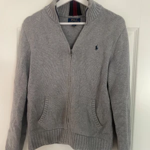 Ralph lauren full zip - En skitsnygg grå stickad Ralph lauren full zip. Den är storlek 164 så den är som en xs. Väldigt bra skick och knappt använd.
