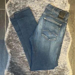 Replay Anbass Jeans Mörkblåa - Mörkblå jeans från Replay, modell Anbass, i storlek W33 L32. Slim fit med stretch – snygg och bekväm passform. Schysst tvätt med lätt slitning. I väldigt fint skick, sparsamt använda.