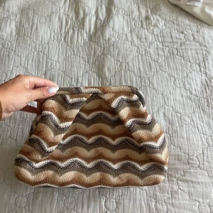 Beige och brun kuvertväska med zigzag - Säljer denna kuvertväska i beige, brunt och vitt med snyggt zigzag-mönster från beck södergard då den inte kommer till användning längre.