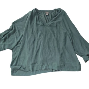 Grön loose v-ringad tröja Lindex XL - Oversized grön tröja från Lindex i storlek XL. Tröjan har v-ringning och långa ärmar, perfekt för en chill och avslappnad stil. Tillverkad i mjukt material som känns skönt mot huden. Passar dig som gillar en loose fit och enkel design.