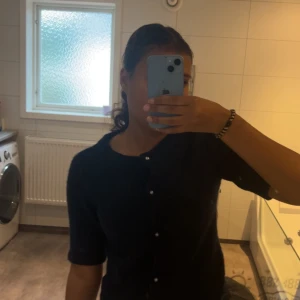 Mörkblå kofta med pärlknappar - Säljer en mörkblå kofta med halvlånga ärmar och snygga pärlknappar framtill. Koftan har en klassisk rund halsringning och är perfekt att slänga över en topp. Enkel och stilren design som passar till mycket.