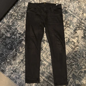 Svarta jeansbyxor från Lee - Säljer ett par svarta jeansbyxor från Lee med klassisk femficksdesign och raka ben. Perfekta för dig som gillar en stilren och enkel look. Storleken är mindre än vanligt