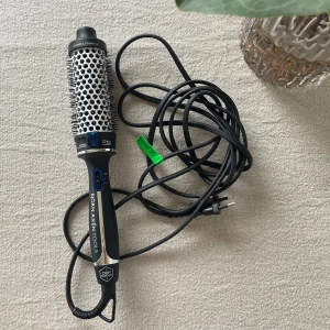 Rundborste med värme från Hot Tools - Elektrisk rundborste med värme från Hot Tools, perfekt för att styla och skapa volym i håret. Borsten har svart handtag, silverfärgad borstdel med metall och svarta borst. Utrustad med lång sladd och digital display.