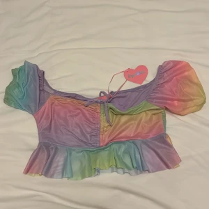 Pastellfärgad regnbågstopp Sugar Thrillz - Jättesöt magtröja från Sugar Thrillz i pastelliga regnbågsfärger. Köpte på Dollskill men tyvärr för liten för mig (chansade på en storlek under den jag brukar ha). Alltså helt oanvänd med lapp kvar. Typ helt perfekt för Pride eller andra festliga tillställningar 🩷