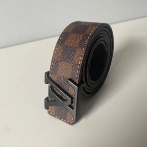 Lv bälte - Louis Vuitton bälte brunt för salu. Helt ny aldrig använd. Är i 130cm men kan göra hål så den passar i vilken storlek du behöver. INGET UNDER 300kr