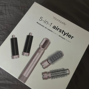 Youniquely 5-in-1 airstyler - Multifunktionell hårstyler med fem utbytbara tillbehör för att skapa olika frisyrer. Inkluderar två locktillbehör, två rundborstar och ett fönmunstycke i roséguld och svart. Perfekt för att styla och forma håret med varmluft.