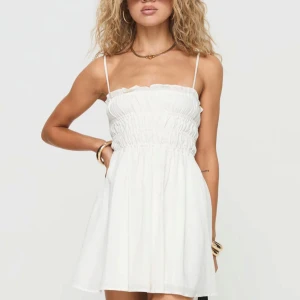 Vit kort klänning med smock och tunna axelband - Söt vit klänning med smock upptill och tunna axelband från princess polly. Helt oanvänd med prislappen kvar. Nypris 600