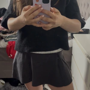 Svart stickad kjol från Zara - Svart stickad kjol från Zara med kort längd och lätt utsvängd form. Mjuk och bekväm, perfekt för lager-på-lager. Enkel design utan synliga detaljer, passar till många olika stilar.