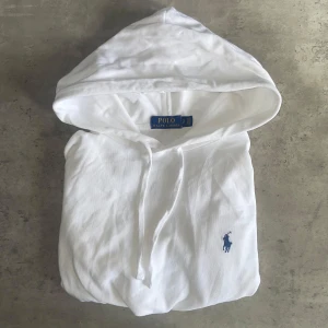 Vit hoodie från Ralph Lauren - Säljer en klassisk vit hoodie från Ralph Lauren med logga på bröstet. Tröjan har långa ärmar, huva. Vid frågor eller funderingar är de bara att höra av sig😊😉