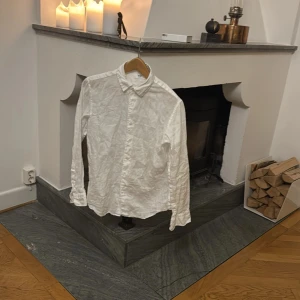 Vit linneskjorta - Säljer en stilren vit linneskjorta med klassisk krage och knappar framtill. Skjortan har långa ärmar och är perfekt för en avslappnad men ändå elegant look. Passar bra till både jeans och chinos. Nypris: 600kr