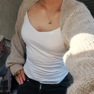 Beige stickad bolerotopp - Säljer en beige stickad bolerotopp med lång ärm. Den är ribbad och sälj då den inte kommer till användning längre. Den är köp från ginatricot.