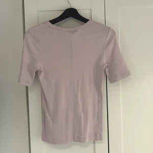 Ljuslila topp från Gina Tricot - Säljer en ljuslila topp från Gina Tricot, basically basics-kollektionen. Toppen har rund halsringning och korta ärmar. Enkel och stilren design i mjukt material, perfekt för en clean look. Ljus färg och superfin till sommaren. Hör av er vid intresse!💕