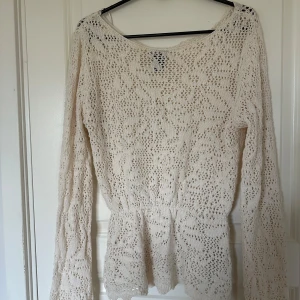 Vit spetsblus med lång ärm - Säljer en söt vit blus med spetsdetaljer och lång ärm. Blusen har en lätt utställd midja och ett romantiskt mönster. Perfekt att styla med jeans eller kjol för en trendig look.