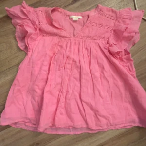 Rosa blus med volangärmar - Säljer en söt rosa blus med volangärmar och v-ringning. Blusen har fina spetsdetaljer upptill och är tillverkad i ett lätt och luftigt material. Perfekt för vår och sommar!