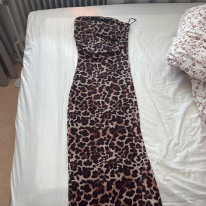 Leopardmönstrad långklänning från new yorker  - Säljer en snygg leopardmönstrad långklänning från new Yorker . Klänningen är ärmlös med smala axelband och har en tight passform. Perfekt för dig som vill sticka ut med ett djurmönster. Materialet är mjukt och stretchigt för en bekväm känsla.
