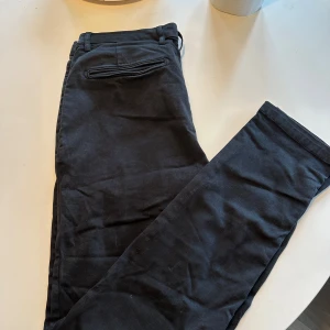 Svarta chinos från Replay Benni - Säljer ett par svarta chinos från Replay, modell Benni. Byxorna har normal passform, klassisk design med fickor fram och bak samt bälteshällor. Perfekta för en stilren och avslappnad look.