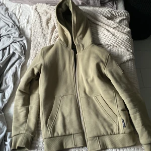 Ljusgrön hoodie jacka från moose Knuckles - Säljer en ljusgrön hoodiejacka från Moose Knuckles med dragkedja framtill och två stora fickor. Jackan har huva, ribbade muddar och quiltat svart innerfoder. Detalj med metallogo på ärmen. Perfekt för kyliga dagar. Ordinarie pris 3500kr