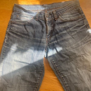 Levis bootcut jeans i mellanblå denim - Klassiska Levis jeans i mellanblå tvätt med bootcut-ben. Femficksmodell med orange sömmar och Levis-röd etikett på bakfickan. Jeansen har normal passform och är tillverkade i slitstark denim. Dem är unika och vintage! 