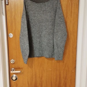 Grå stickad tröja - Mysig grå stickad tröja med lång ärm och rund halsringning. Perfekt för kyliga dagar och enkel att matcha med olika outfits. Klassisk och tidlös design.