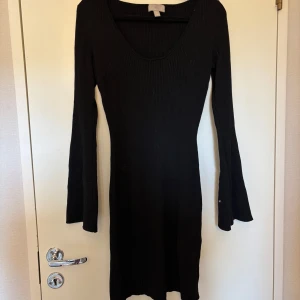 Svart ribbad långärmad klänning - En svart, ribbad klänning med lång ärm och rundad urringning. Klänningen har en tight passform och är tillverkad i ett stretchigt material som sitter snyggt på kroppen. Perfekt för dig som gillar en enkel men stilren look.