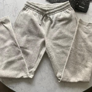 Ljusgrå mjukisbyxor  - Säljer ett par Low waist ljusgrå mjukisbyxor i storlek XS med resår och dragsko i midjan. Byxorna har raka ben och är perfekta för en avslappnad stil. Mjukt material som känns skönt mot huden. 