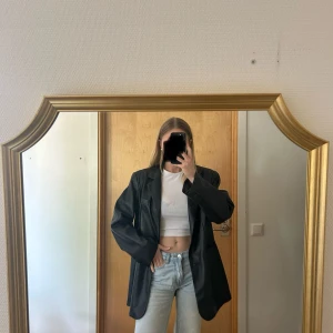 Skinn (läder) blazer - Säljer en svart oversized skinn kavaj med klassisk krage och knappar framtill. Kavajen har lång ärm och rak passform, perfekt att styla till jeans eller kjol. Storleken passar både 36 och 38
