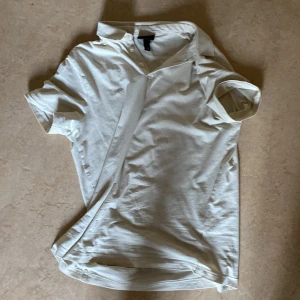 Vit kortärmad t-shirt från H&M - Säljer en stilren vit t-shirt från H&M med klassisk passform och korta ärmar. Perfekt basplagg till garderoben. T-på shirten är gjord i mjuk bomull och har rund halsringning.