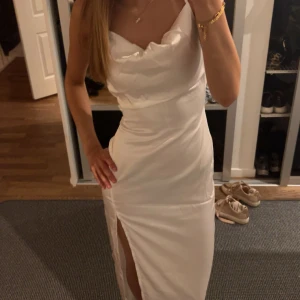 Vit långklänning  - Säljer en vit långklänning med slits, hade den på min bal förra året och är använd 1 gång. Säljer för den inte kommer till användning mer 