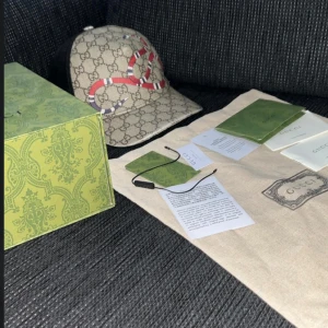 Gucci keps med orm-motiv - Snygg beige keps från Gucci med klassiskt GG-mönster och en röd-vit-svart orm på framsidan. Kepsen har böjd skärm och svart mesh baktill för extra ventilation. Perfekt accessoar för att sticka ut. Skicket är ganska bra kom privat för fler bilder!