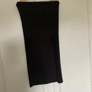 Svart långkjol med slits - En stilren svart långkjol med rak passform och diskret slits på sidan. Kjolen är enkel och passar perfekt till många olika looks. Materialet känns mjukt och följsamt.