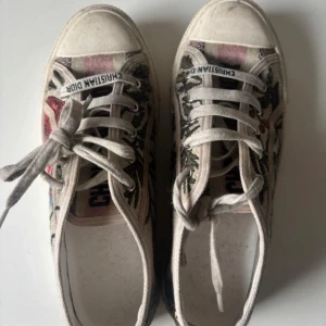  Christian Dior sneakers - Säljer ett par unika sneakers från Christian Dior med blommigt mönster. Skorna har snörning, vit sula och tydlig Dior-logga på sidan. storlek 39