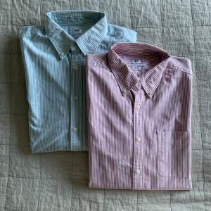 Två stilrena slim fit skjortor från Uniqlo i randigt mönster. Den ena är ljusblå och den andra är rosa, båda med knappar framtill och klassisk krage. Säljer båda för 700kr, om du endast är intresserad av den ena blir det 400kr