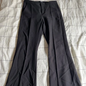 Svarta kostymbyxor från Gina Tricot - Snygga svarta kostymbyxor från Gina Tricot i storlek M. Byxorna har en klassisk design med raka ben och lite lägre i midjan, perfekt för en stilren look. Tillverkade i ett bekvämt material som ger en elegant passform. Lite nopprig på vissa ställen men syns inte när de sitter på. Väldigt fina och väljer att sälja då de var för långa för mig.