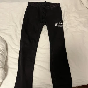 Svarta jeans från Dsquared2 - Snygga svarta jeans från Dsquared2 med tryck på benet. De har en knappgylf och är tillverkade i Italien. Perfekta för en stilren look. Pris sänks vid snabbaffär.