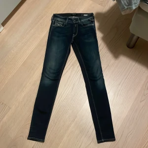 Mörkblå skinny jeans från Replay - Snygga mörkblå skinny jeans från Replay med en tight passform. De har klassiska fem fickor och en knapp med Replay-logga. Perfekta för en stilren look.