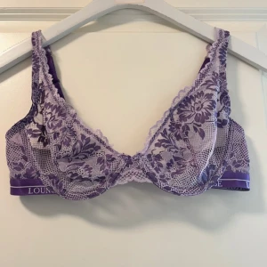 Lila spets-bh från Lounge - Säljer en vacker lila spets-bh från Lounge. Den har justerbara axelband och ett elegant blommönster. Perfekt för att känna sig både bekväm och stilfull. Aldrig använt den, nypris är 399kr 