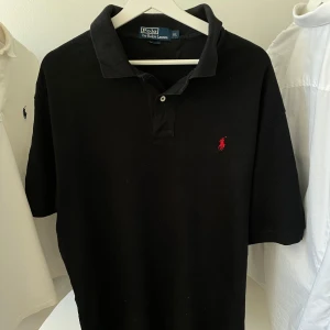 Ralph Lauren pikétröja - Polo Ralph Lauren pikétröja Storlek: XL | Färg: svart Klassisk modell, i fint skick – inga fläckar eller slitage. Kvalitativ och tidlös, passar både till vardags och finare tillfällen.✨👕  Snabb leverans 🚚 och extra bilder får du gärna fråga om!