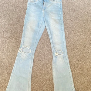 Ljusblå bootcut jeans - Snygga ljusblå bootcut jeans med slitna detaljer på knäna. 