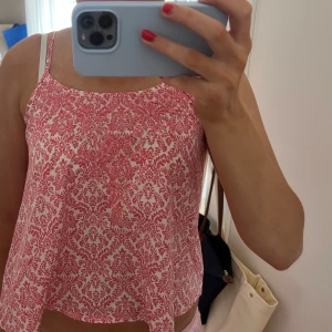 Rosa och vit blommig linnetopp - Söt och somrig rosa och vit blommig linnetopp med smala axelband. Perfekt för varma dagar och ger en fräsch look. Toppen har en lös passform och är lätt att matcha med olika outfits. Använd få gånger🩷